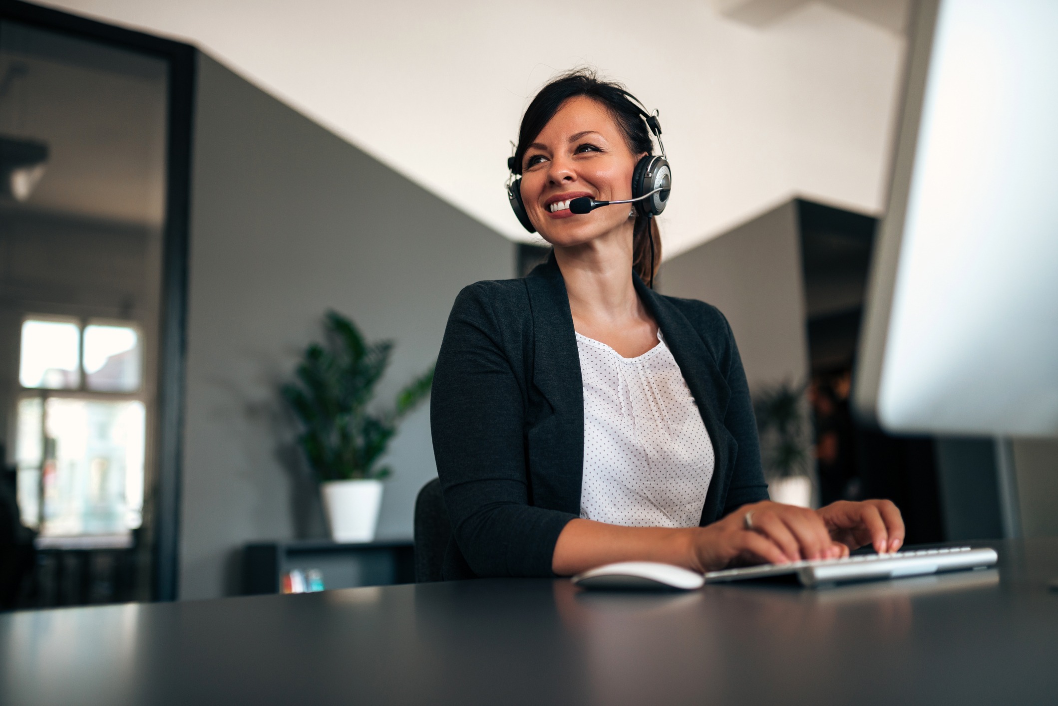 Woman with headset sitting at desktop computer
